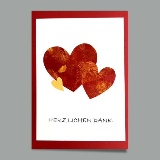 Bild der Dankeskarte «Herzlichen Dank Dreielei Herz» mit Encaustic Herzen auf Softweiss über Grundkarte Rot